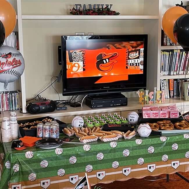 A view of the tv, table with snacks and the Orioles game on the tv